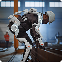 An industrial exoskeleton in use — the worker still does the work, the suit handles the load